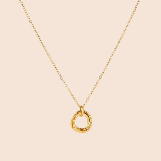 Delicate gold-plated necklace with three interlocking circle rings forming a minimalist knot pendant on cream background