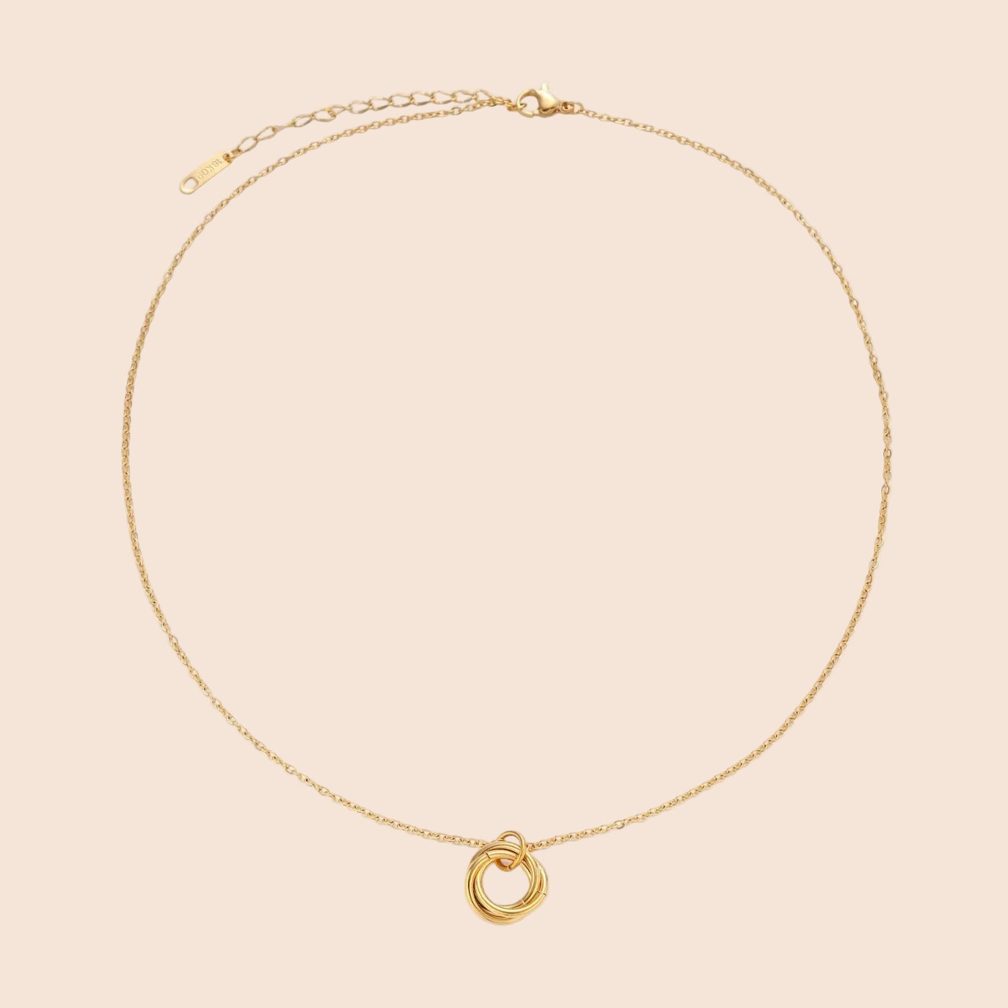 Delicate gold-plated necklace with three interlocking circle rings forming a minimalist knot pendant on cream background