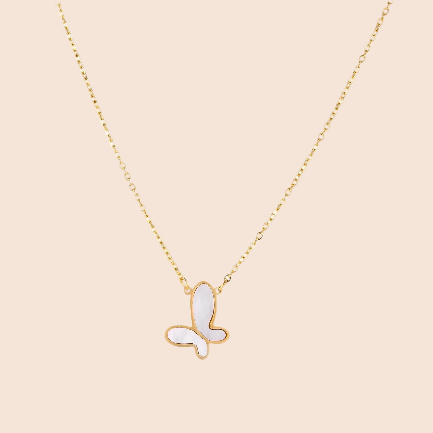 Gold-plated butterfly pendant with iridescent mother of pearl inlay on delicate chain against cream background.