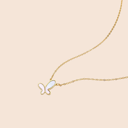 Gold-plated butterfly pendant with iridescent mother of pearl inlay on delicate chain against cream background.