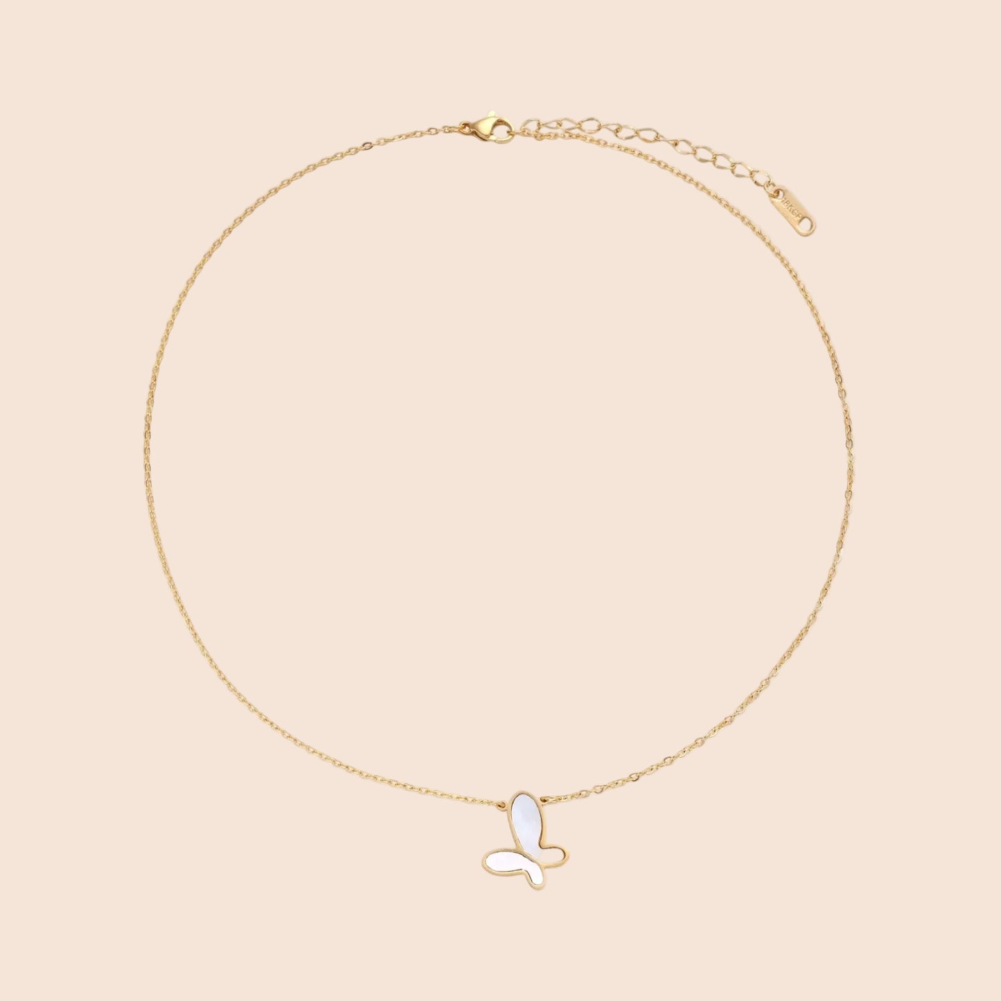 Gold-plated butterfly pendant with iridescent mother of pearl inlay on delicate chain against cream background.