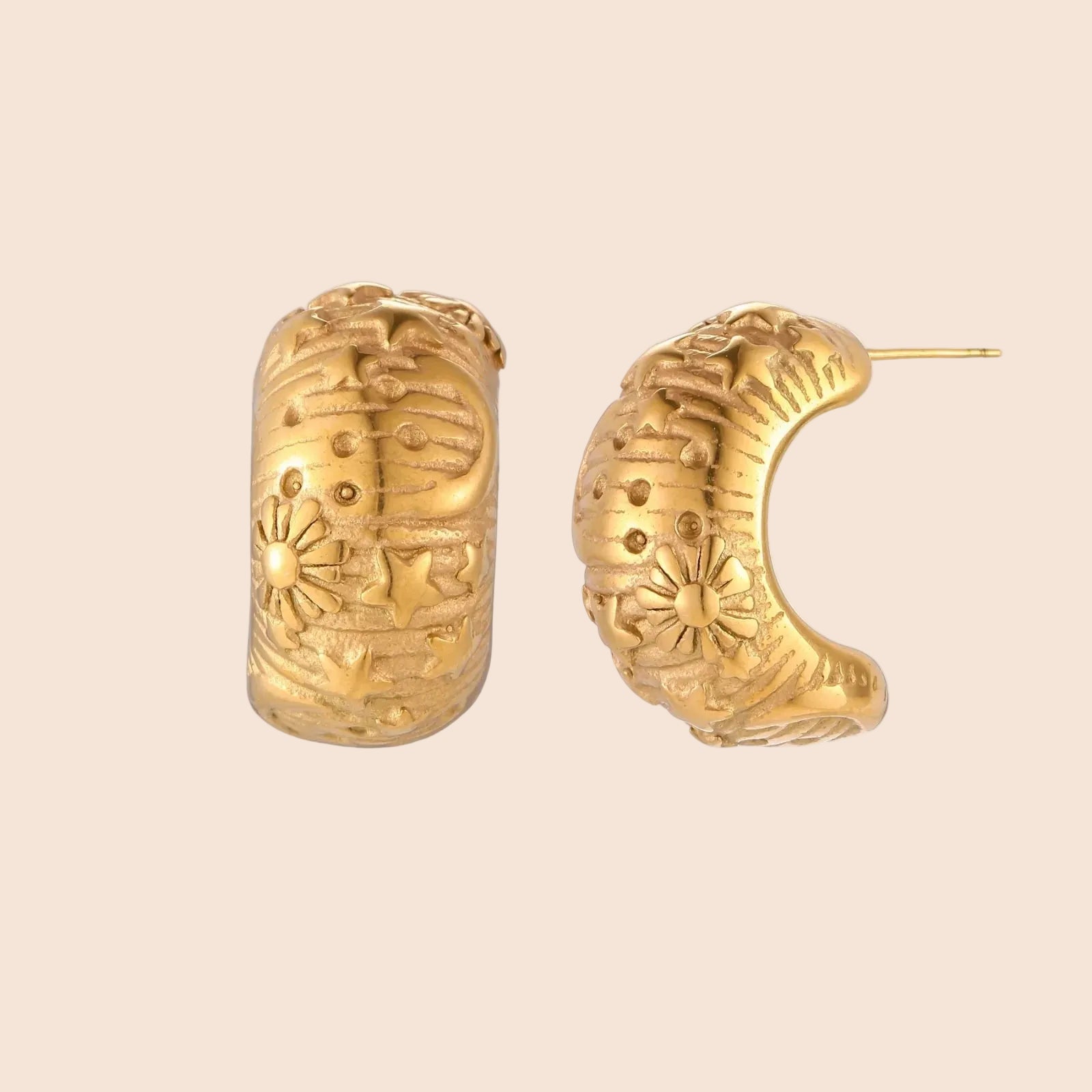 Gold-plated chunky hoop earrings with sun and star engravings on white background, showing detailed celestial pattern work.
