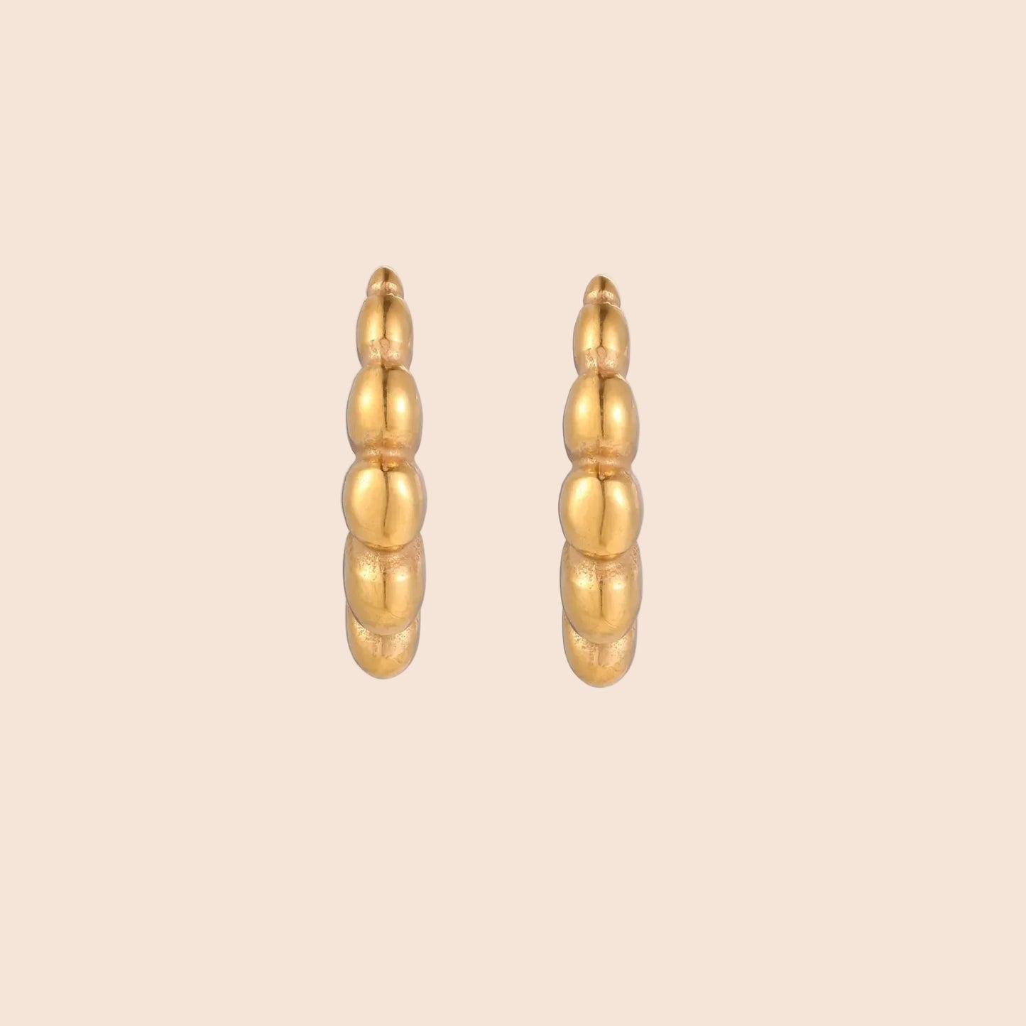 Gold-plated sculptural hoop earrings with chunky segmented design on cream background