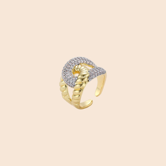 Chunky gold-plated chain-link ring with curved segments and sparkling zirconia crystals on neutral background